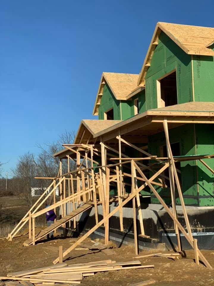 Green house under construction with wooden scaffolding against a clear blue sky
