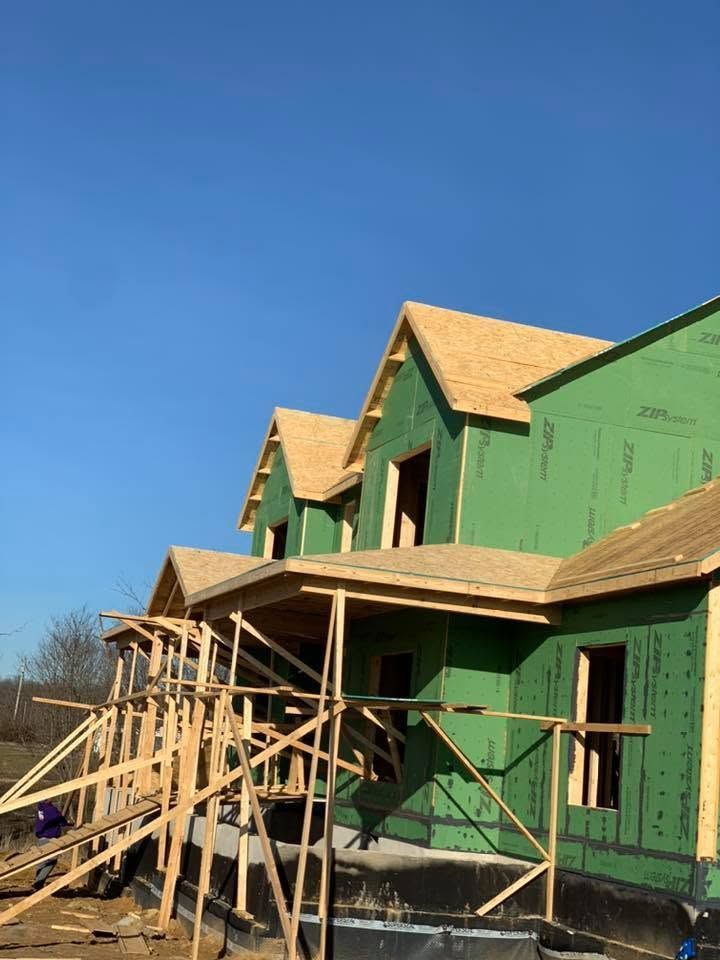 Green house under construction with wooden scaffolding and blue sky.