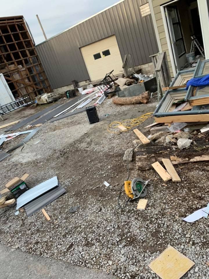 Construction site with scattered debris, tools, and materials beside a metal building.