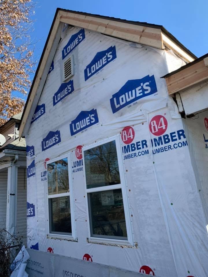 House exterior under renovation with Lowe’s house wrap and window openings under construction
