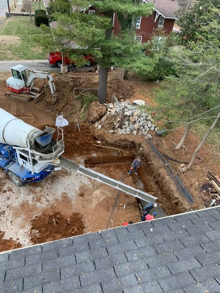 Construction site with concrete mixer truck and excavated trench beside a house.
