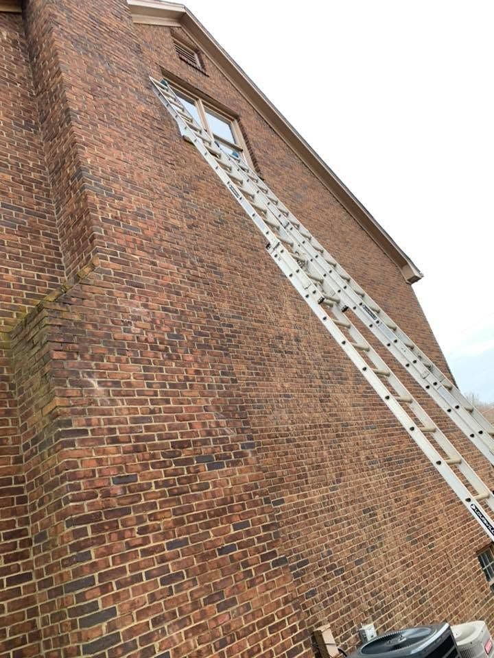 Brick building wall with a long ladder reaching up to a window