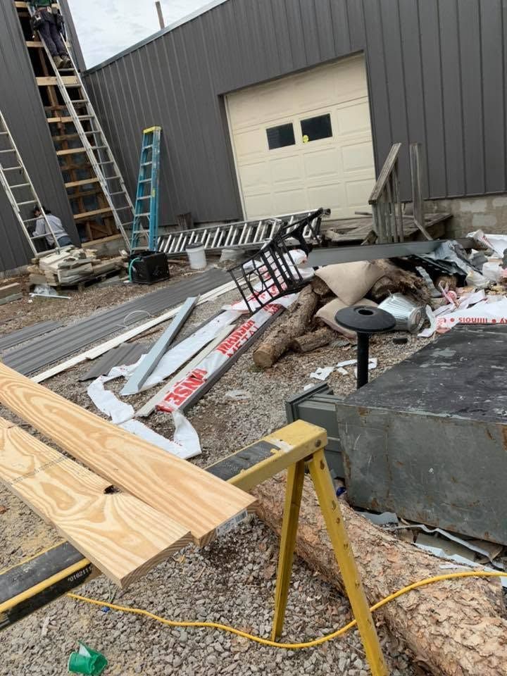 Damaged building exterior with scattered debris, broken signs, and ladders at a construction site