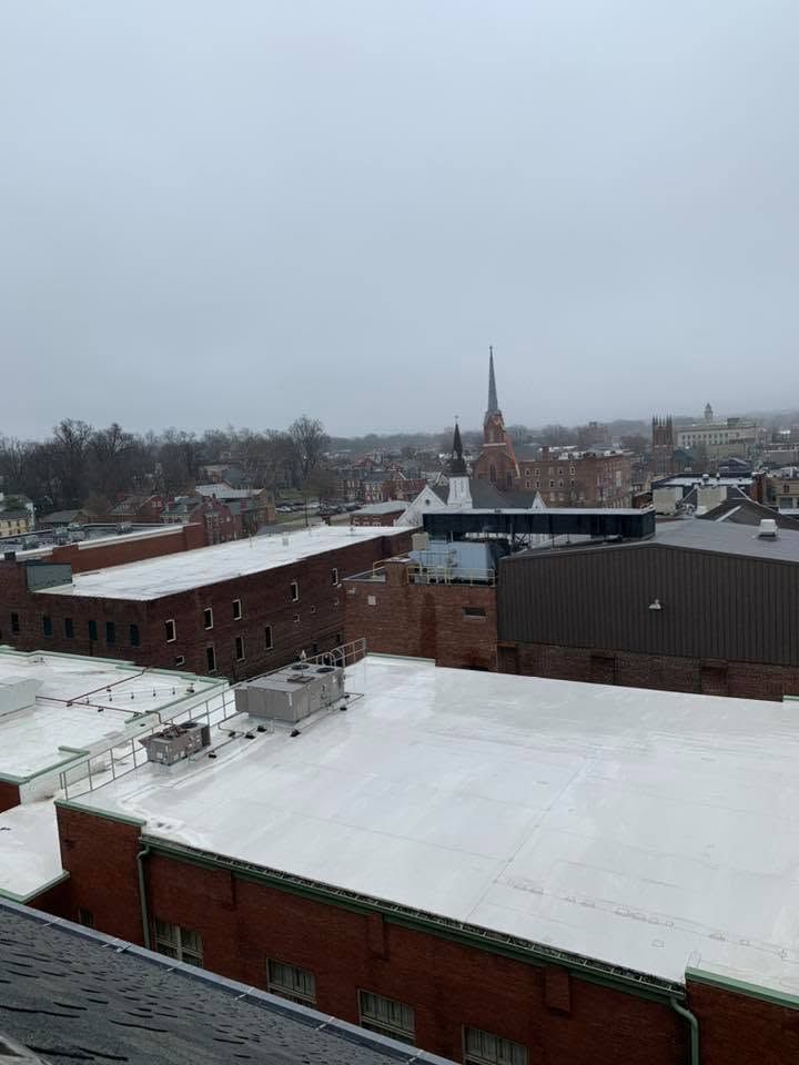 Snow-covered rooftops under an overcast sky, with a church steeple in the distance.