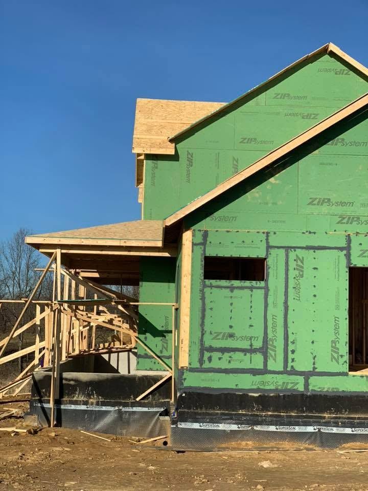 Partially built green house with wood framing and porch under a clear blue sky