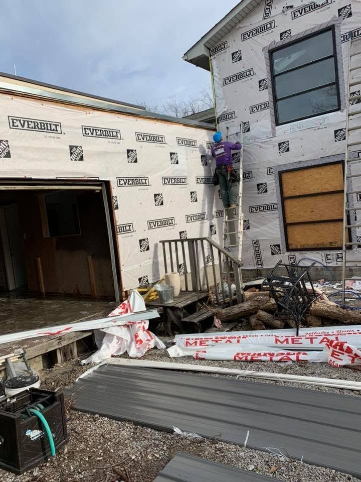 Partially built house with exterior walls, open garage, and stacks of construction materials in front