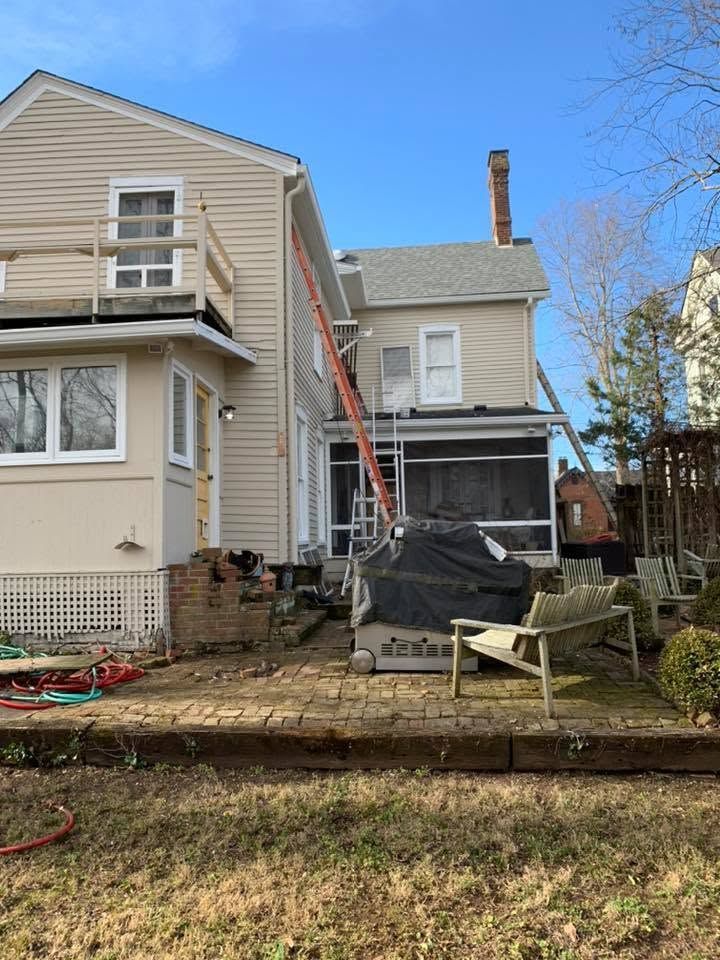 Backyard view of a two-story house with exterior construction scaffolding and covered debris.