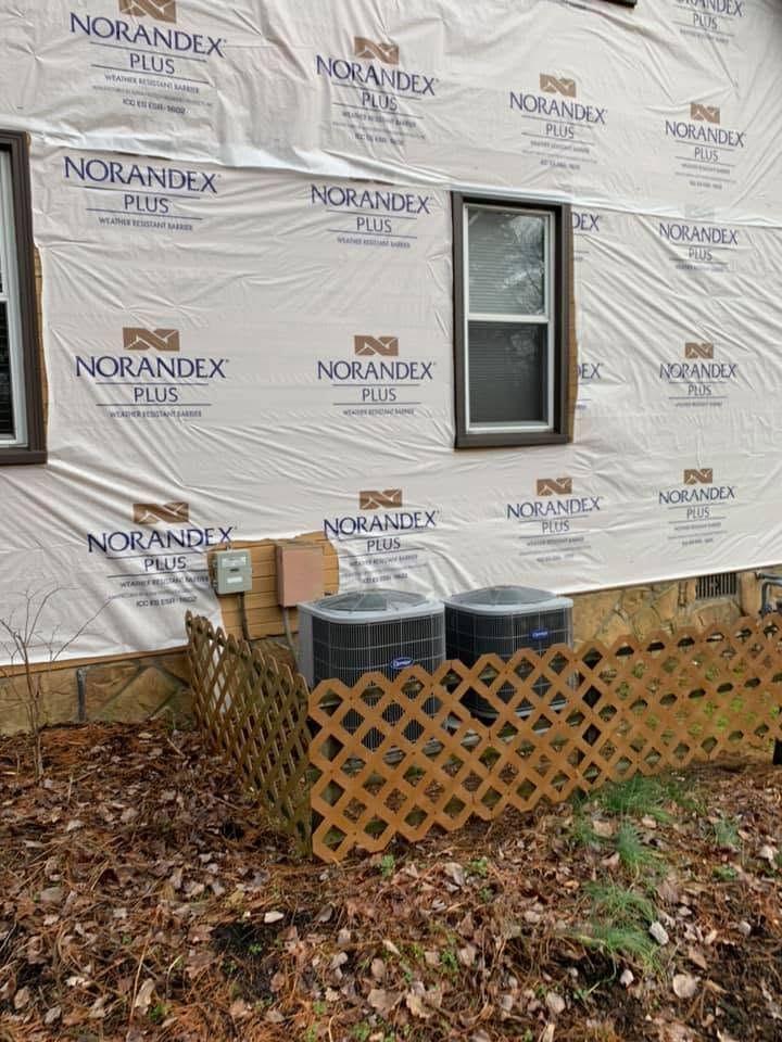 Exterior wall wrapped in Norandex house wrap with a window, lattice skirting, and utility boxes below