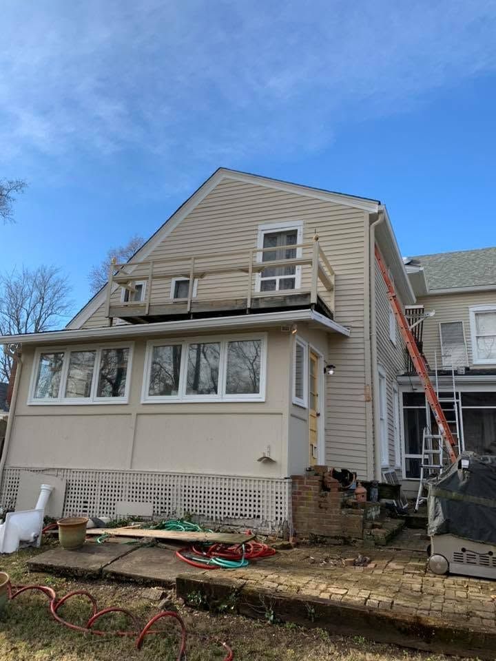 House exterior with ladder on the right, beige siding, and construction materials in front yard