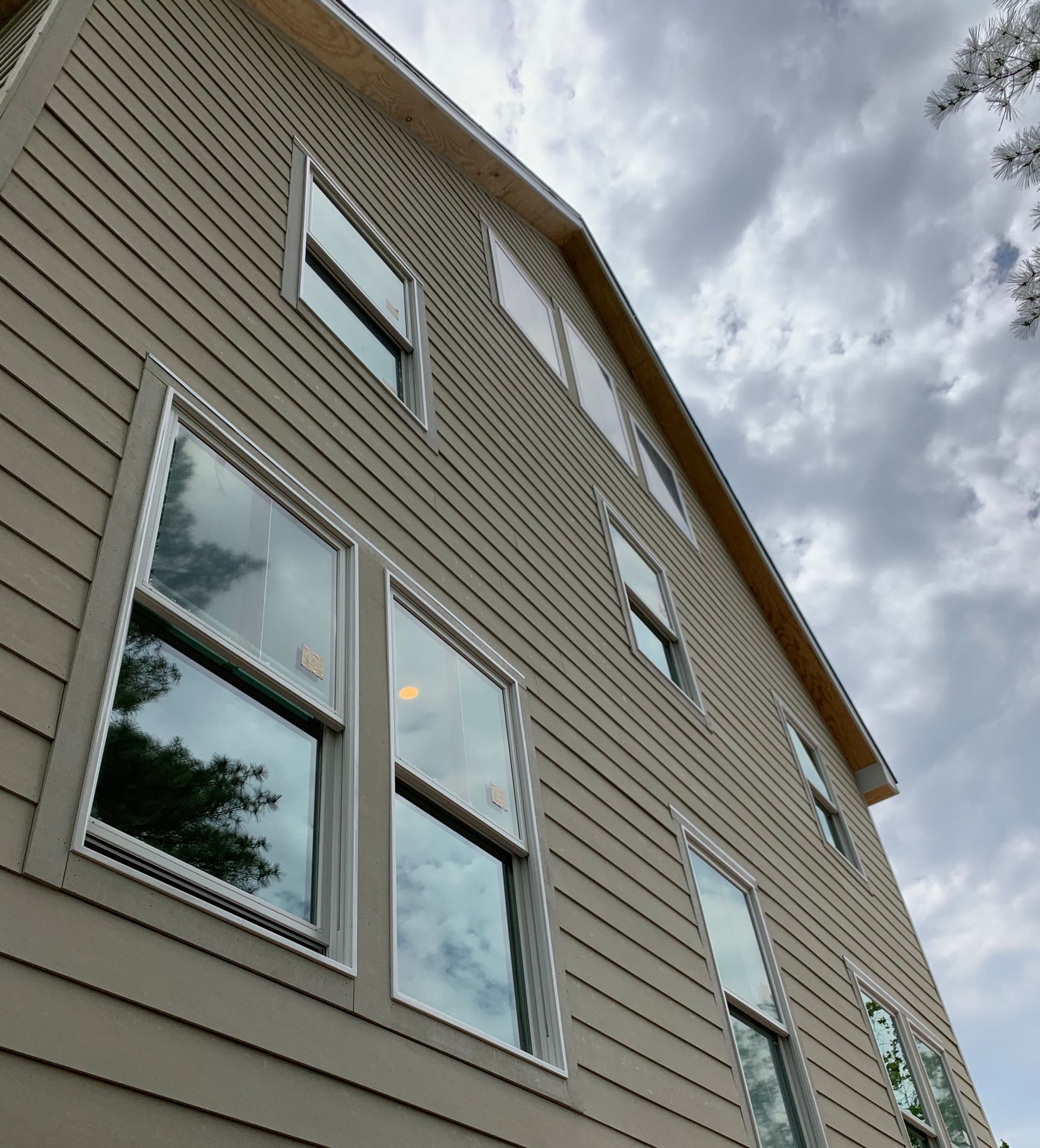 Low-angle view of a beige house exterior with windows against a cloudy sky