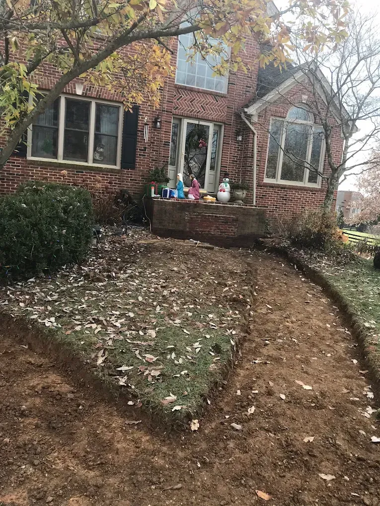 Brick house with a curved dirt path leading to the front door and fall leaves on the ground