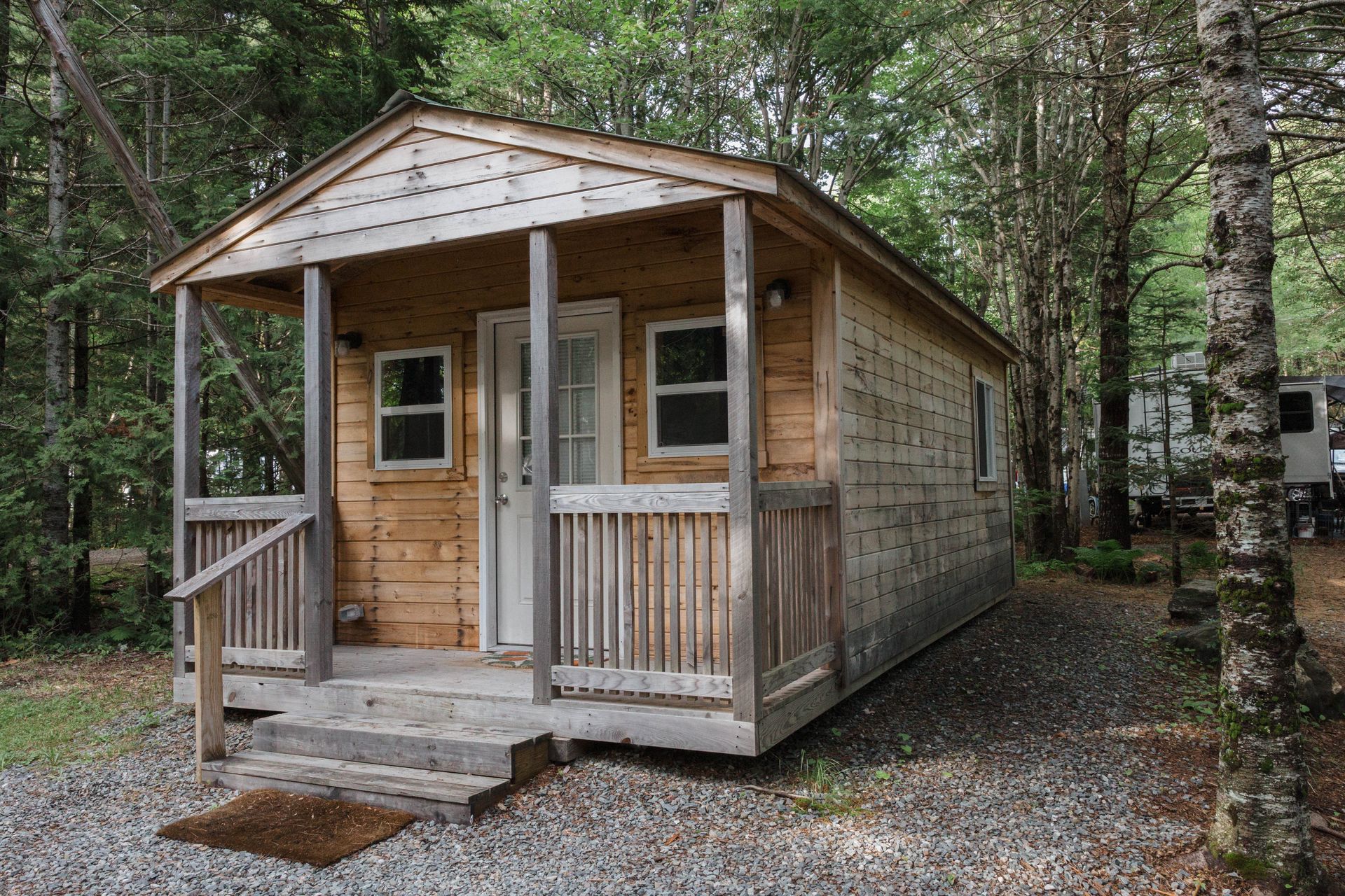 Small rustic wooden cabin with a porch in a wooded area