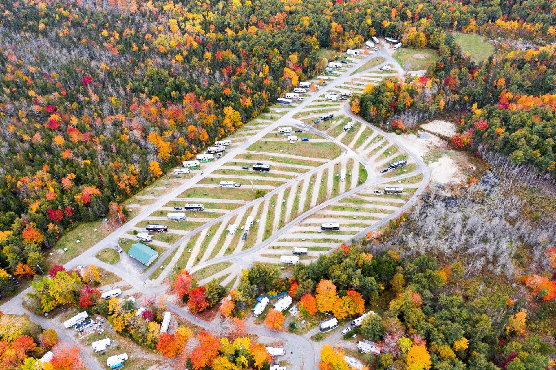 Aerial view of a leaf-shaped parking lot surrounded by colorful autumn forest.