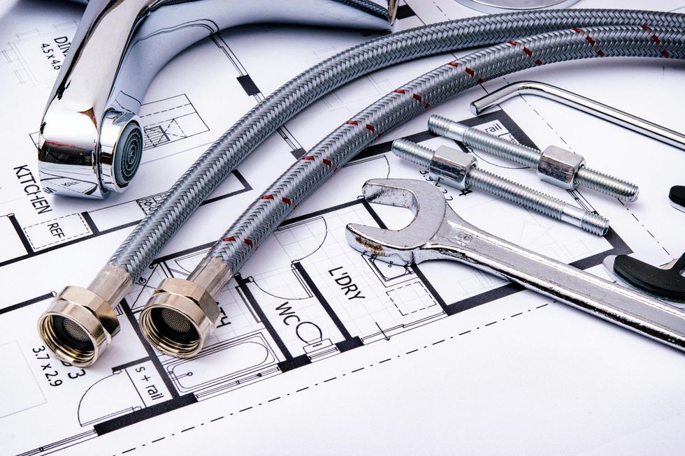 Chrome plumbing pipes and fittings laid over technical blueprints and measuring tools