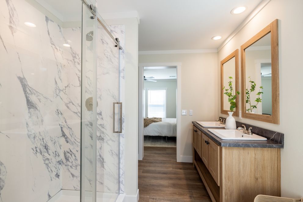 A bathroom with two sinks and a walk in shower.