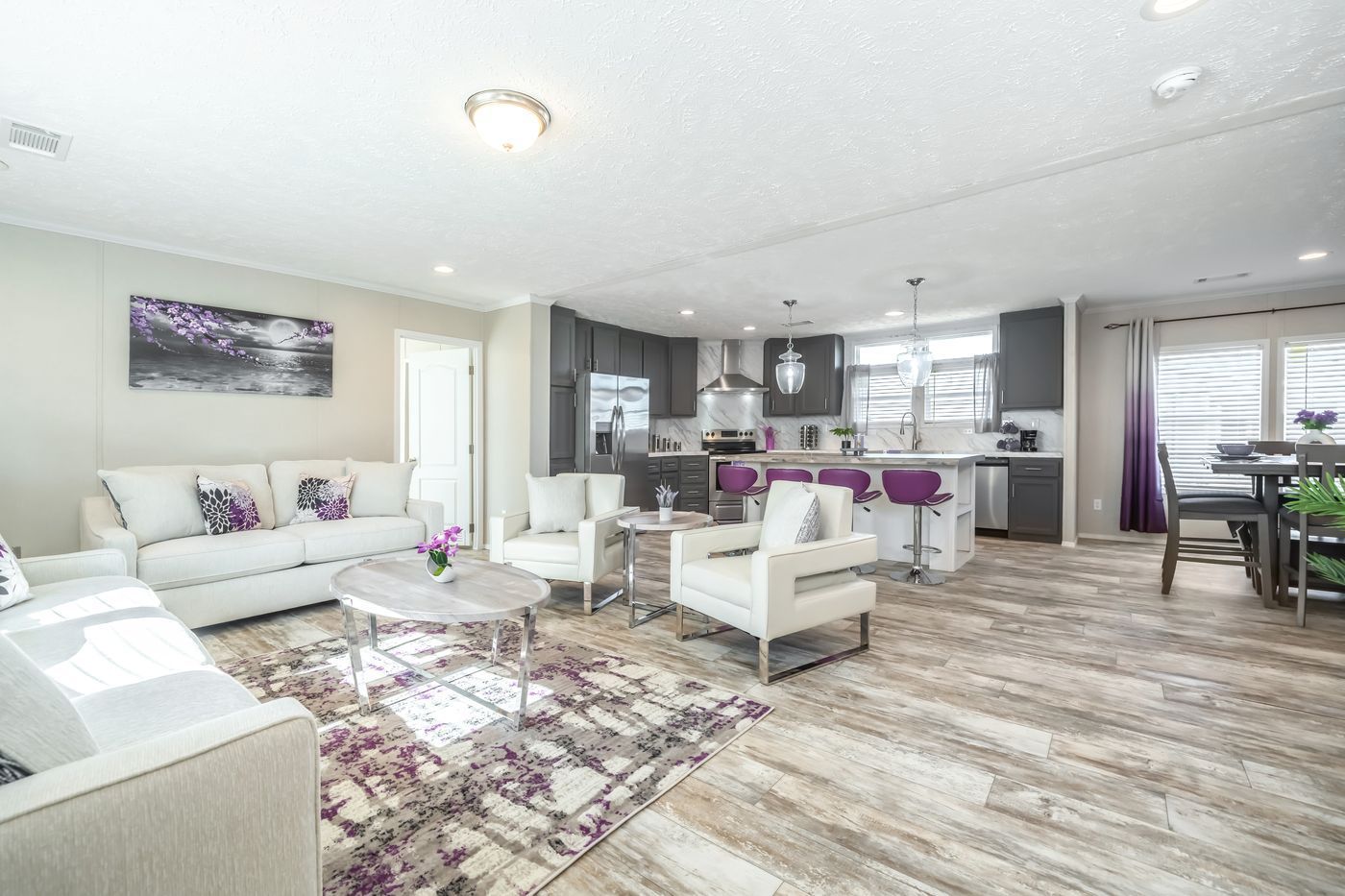 A living room with a couch , chairs , a table and a rug.