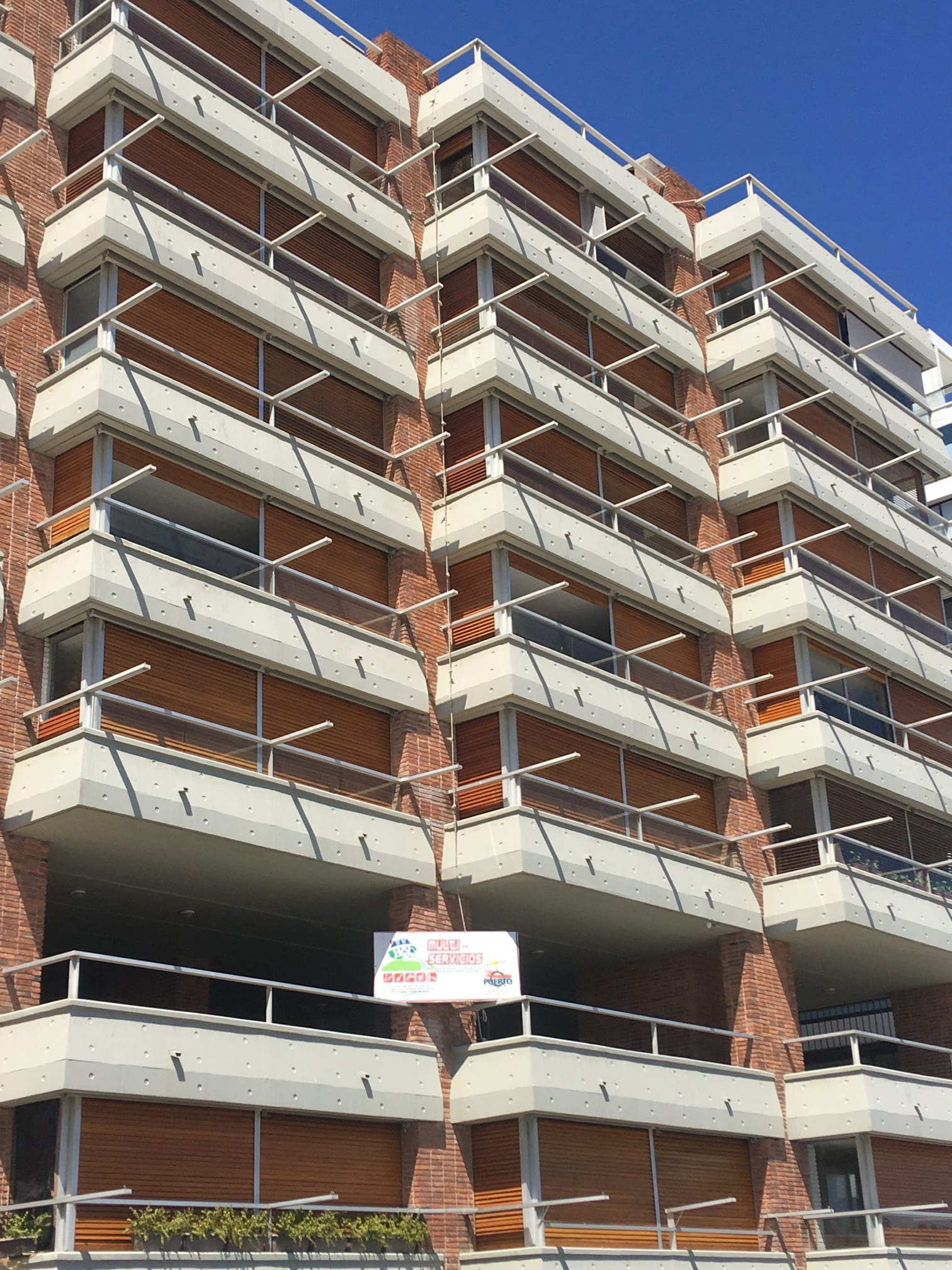 Un gran edificio de ladrillo con muchos balcones y un cartel en el costado.