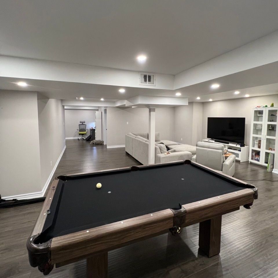 A pool table is in the middle of a living room with pot lights