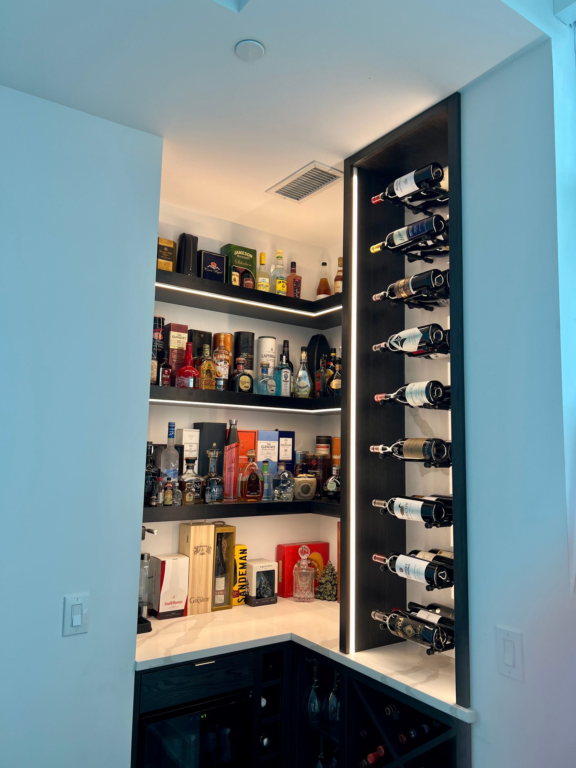 A corner of a kitchen with bottles of wine on shelves