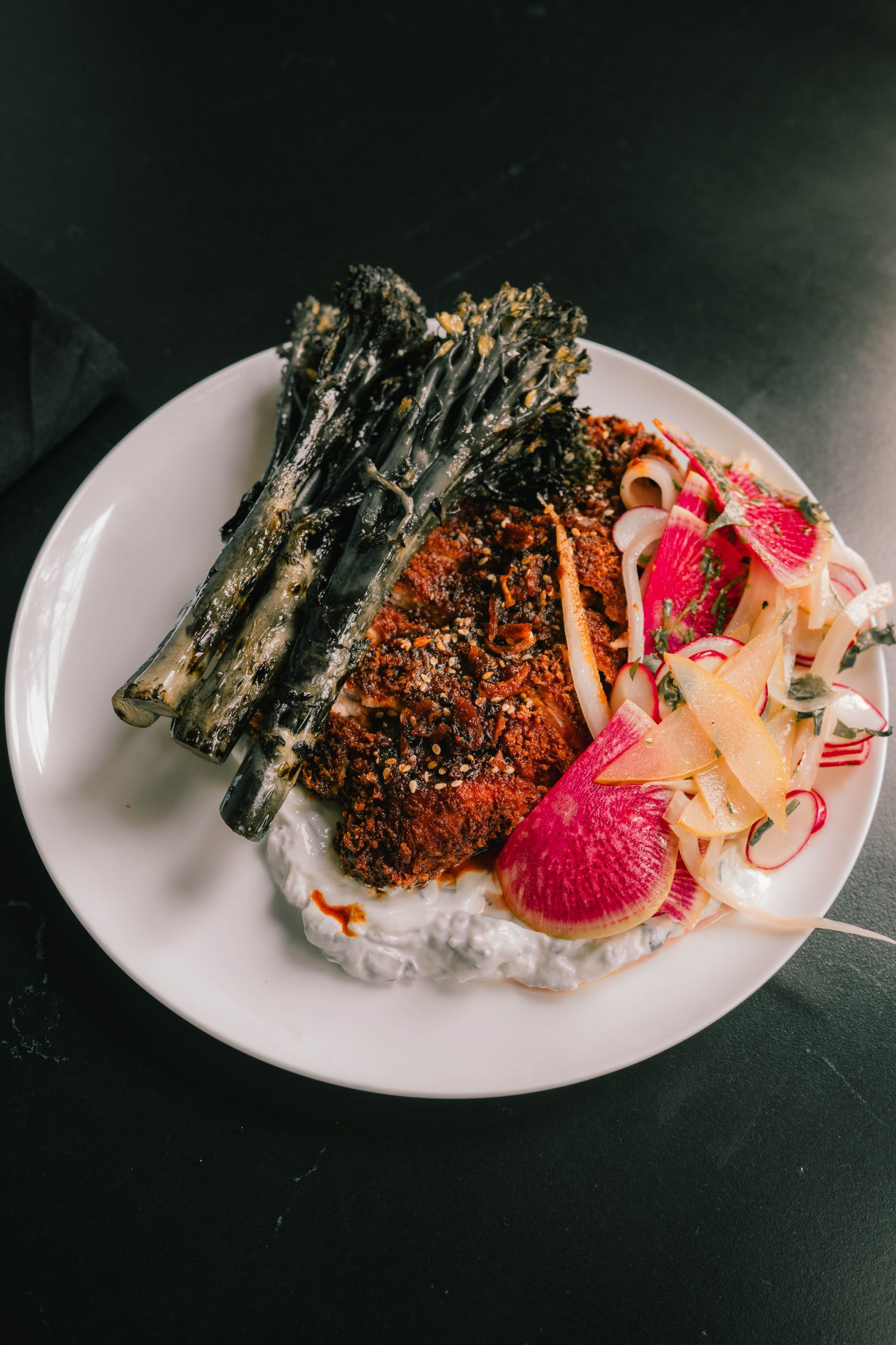 Plated meal with grilled fish, asparagus, rice, and sliced radishes on a white plate.
