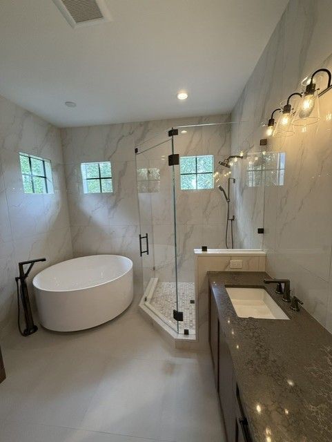 Technician fixing a kitchen sink faucet in a modern room with pendant lights and a wooden cabinet.