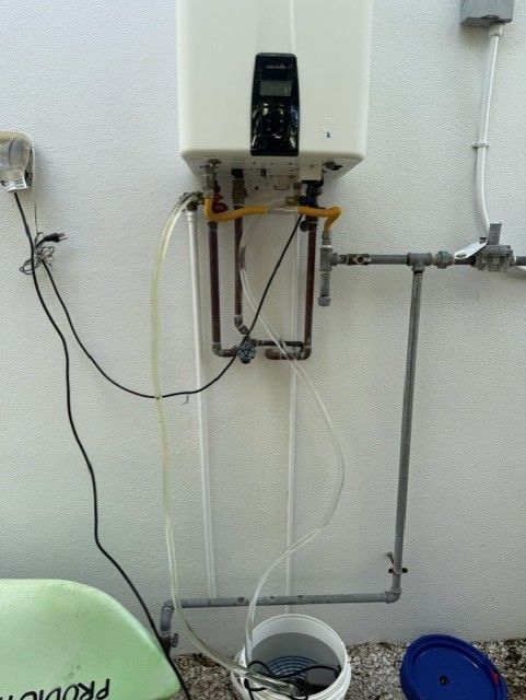 Technician in blue uniform testing a white wall-mounted boiler with a digital multimeter