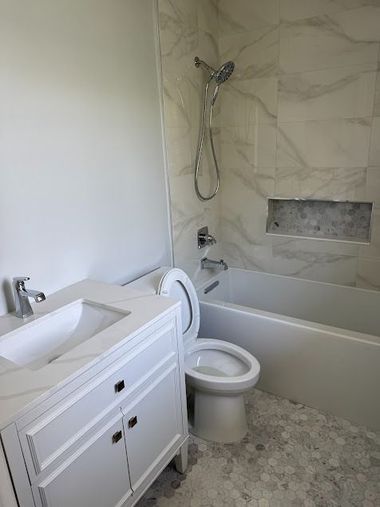 Modern bathroom with white vanity, toilet, bathtub, and marble-patterned walls and floor