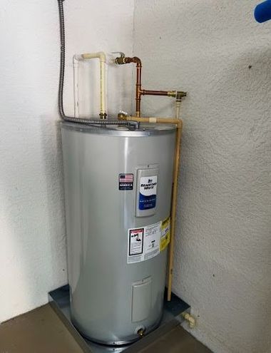Silver water heater with copper pipes against a white wall in a utility room
