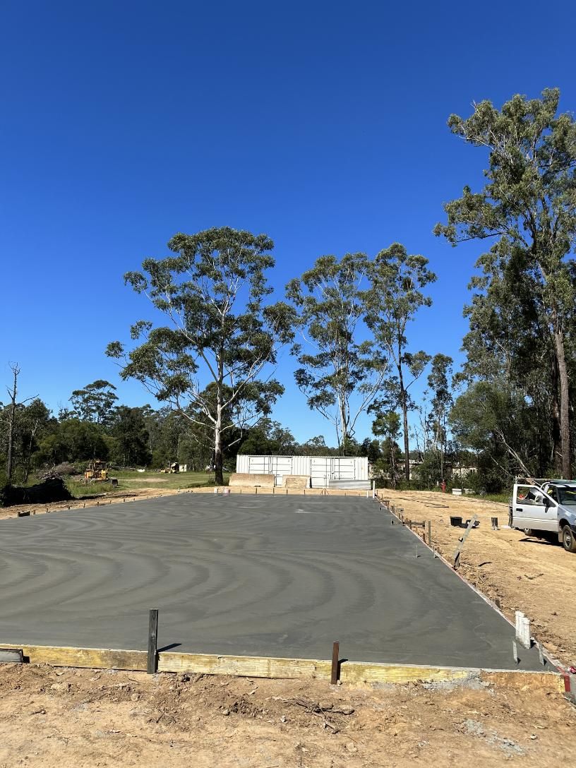 A Concrete Base Is Being Built In A Dirt Field With Trees — Hinterland Concreting Pty Ltd In Lennox Head, NSW