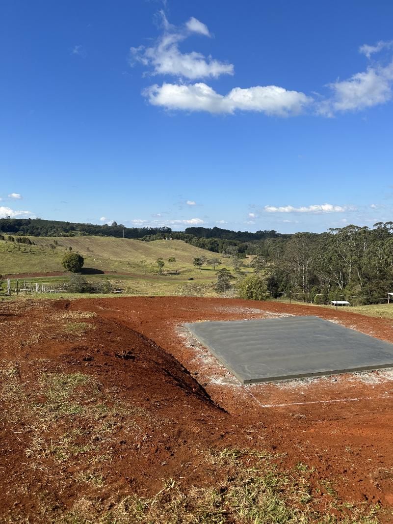 A Concrete Slab Is Sitting In The Middle Of A Dirt Field — Hinterland Concreting Pty Ltd In Lennox Head, NSW