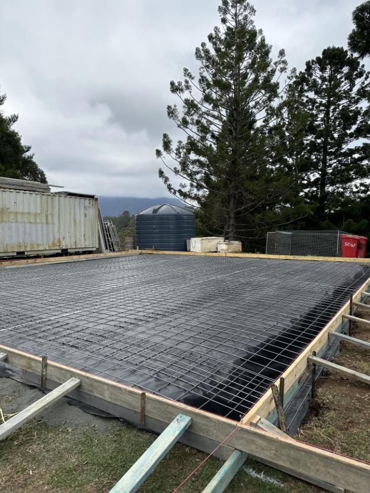 A Concrete Slab Is Being Built In A Yard With Trees In The Background — Hinterland Concreting Pty Ltd In Lennox Head, NSW