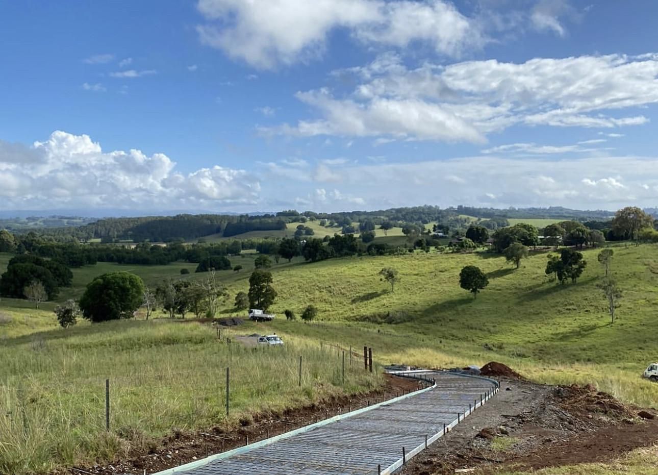 A Dirt Road Is Going Through A Grassy Field — Hinterland Concreting Pty Ltd In Lennox Head, NSW