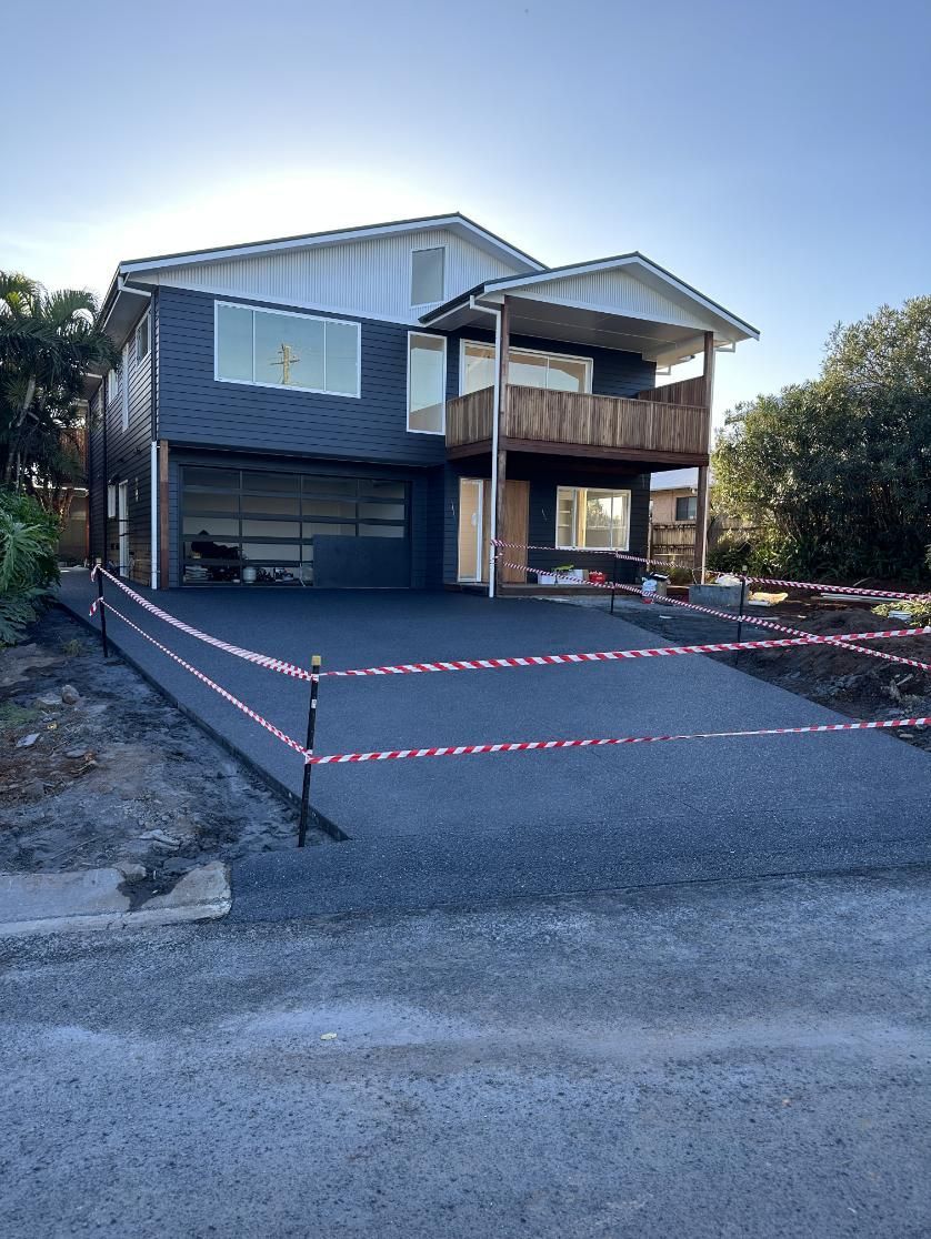A Large House With A Fence Around It And A Driveway — Hinterland Concreting Pty Ltd In Lennox Head, NSW