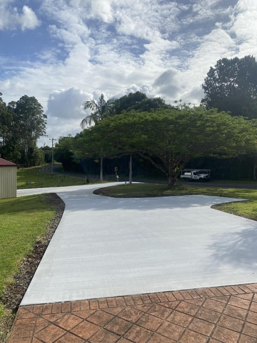 A White Driveway With A Brick Walkway And Trees — Hinterland Concreting Pty Ltd In Lennox Head, NSW