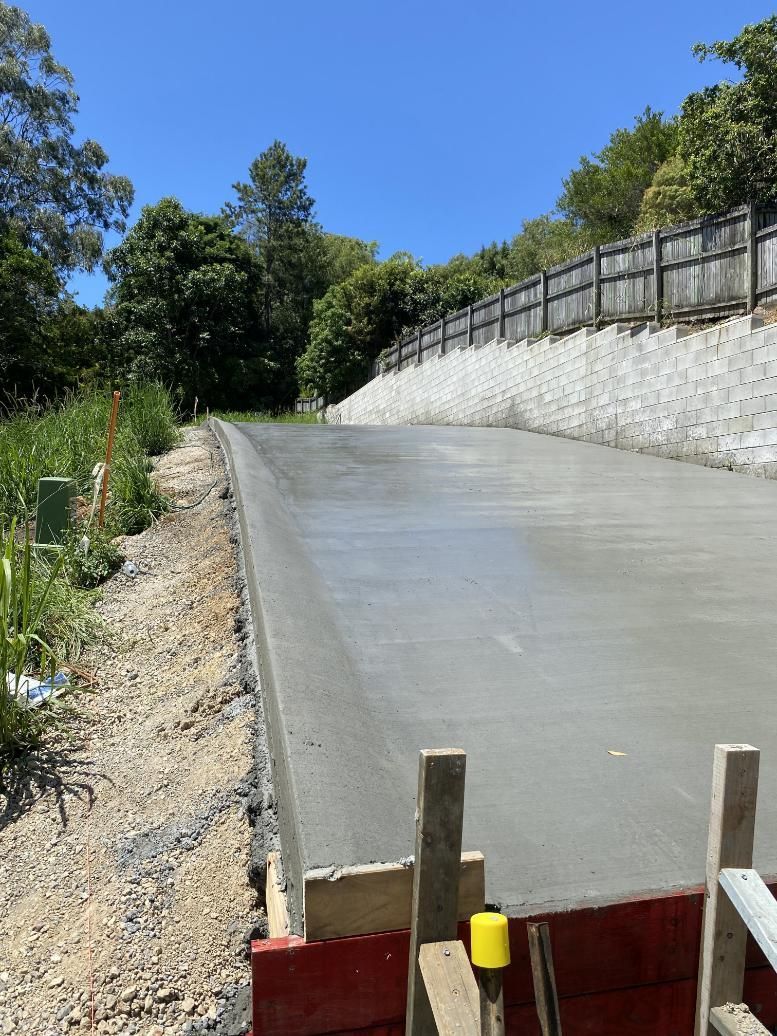 A Concrete Road Is Being Built Next To A Stone Wall — Hinterland Concreting Pty Ltd In Lennox Head, NSW