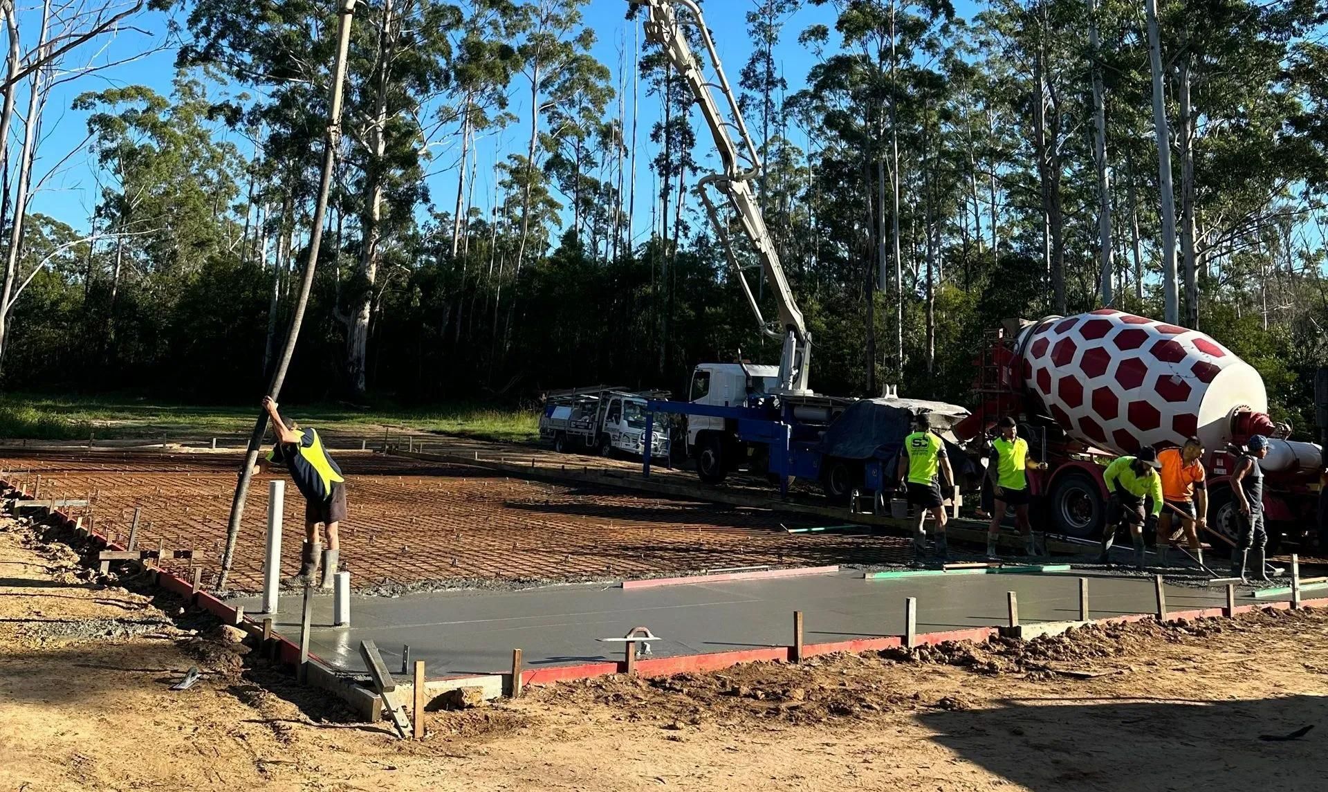 Workers Pouring Concrete Footings At Construction Site