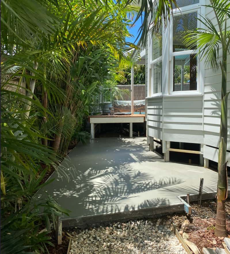 A Concrete Walkway Leading To A House Surrounded By Trees — Hinterland Concreting Pty Ltd In Lennox Head, NSW