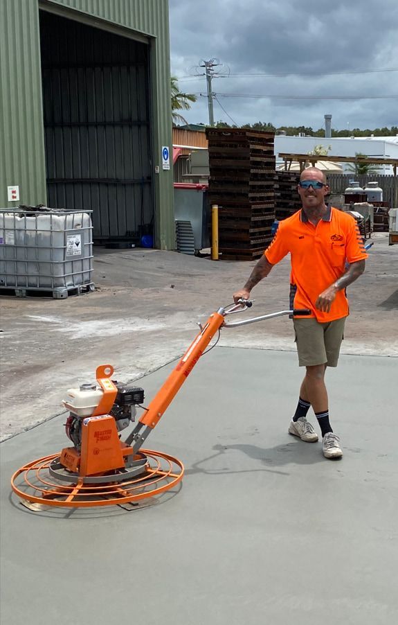 A Man Is Using A Machine To Polish Concrete In A Parking Lot — Hinterland Concreting Pty Ltd In Lennox Head, NSW