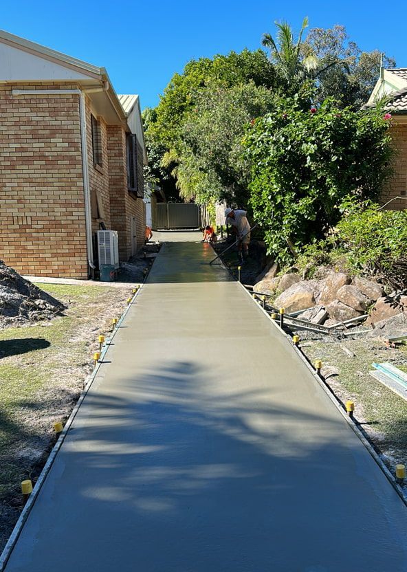A Concrete Walkway Is Being Built In Front Of A Brick House — Hinterland Concreting Pty Ltd In Lennox Head, NSW