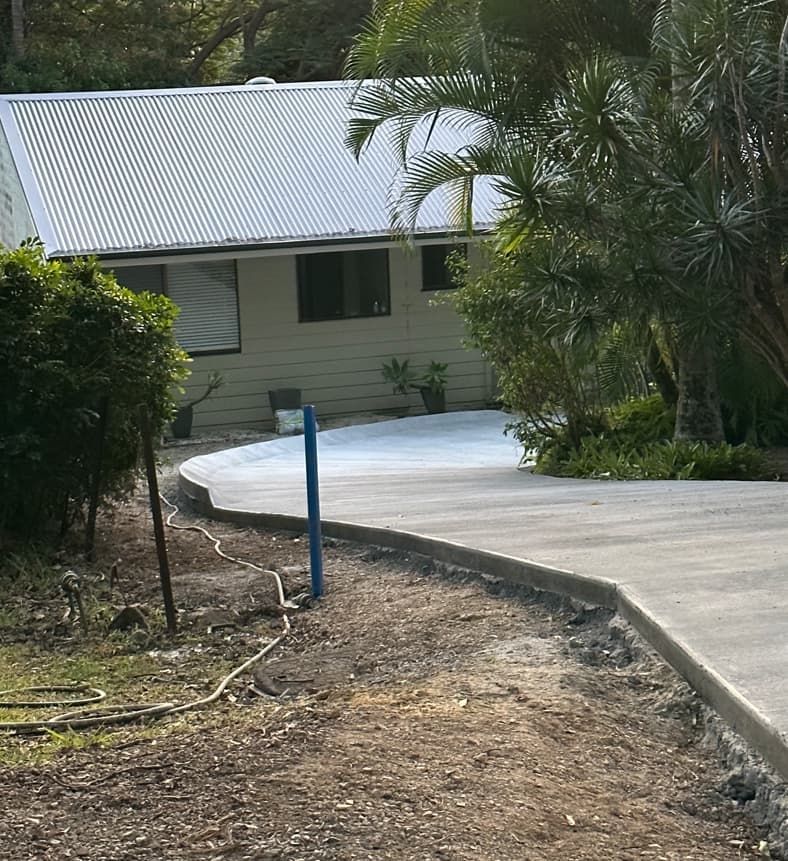 A House With A White Roof Is Surrounded By Trees And Bushes — Hinterland Concreting Pty Ltd In Lennox Head, NSW