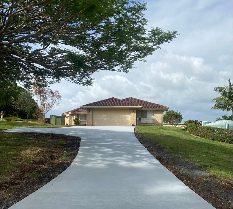 A Driveway Leading To A House With Trees On The Side — Hinterland Concreting Pty Ltd In Lennox Head, NSW