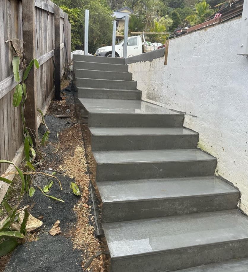 A Set Of Concrete Stairs Leading Up To A Wooden Fence — Hinterland Concreting Pty Ltd In Lennox Head, NSW