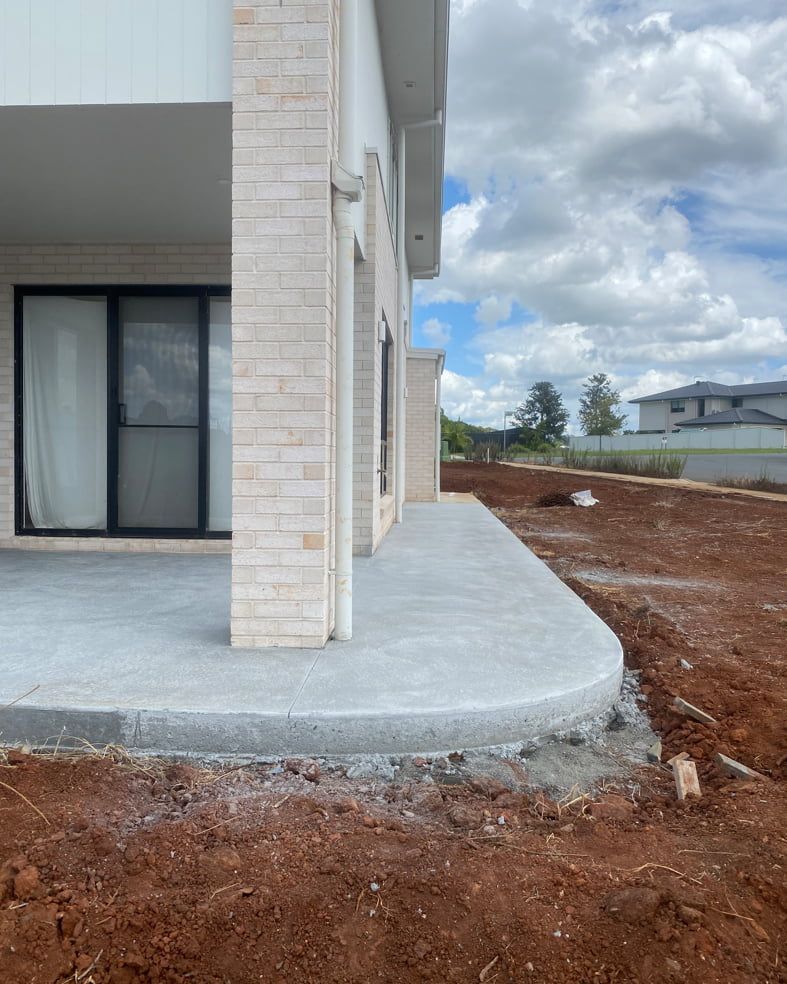 A Brick Building With A Concrete Walkway In Front Of It — Hinterland Concreting Pty Ltd In Lennox Head, NSW