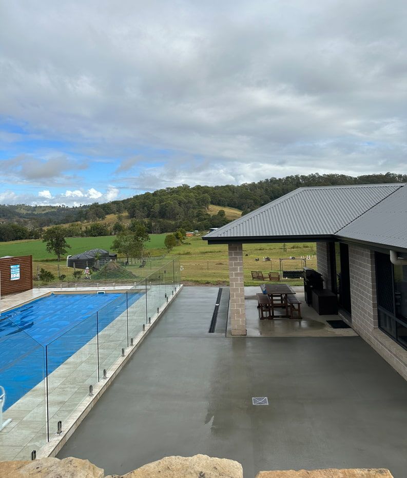 There Is A Large Swimming Pool In The Backyard Of A House — Hinterland Concreting Pty Ltd In Lennox Head, NSW