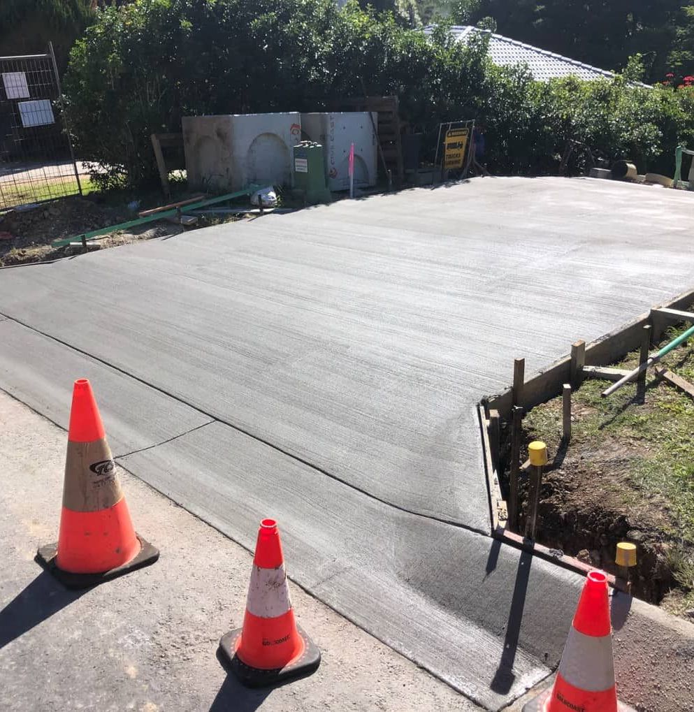 Three Orange And White Traffic Cones Are On The Side Of A Road — Hinterland Concreting Pty Ltd In Lennox Head, NSW
