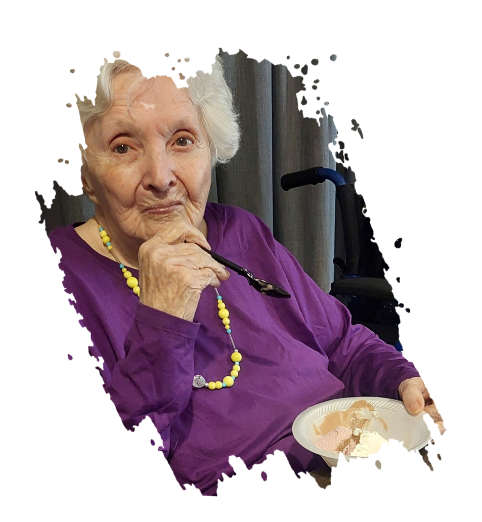 A person holds a document, looking at a woman with long grey hair, indoors with holiday decorations.