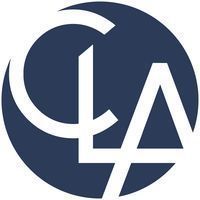 A circular dark blue logo featuring the stylized white letters