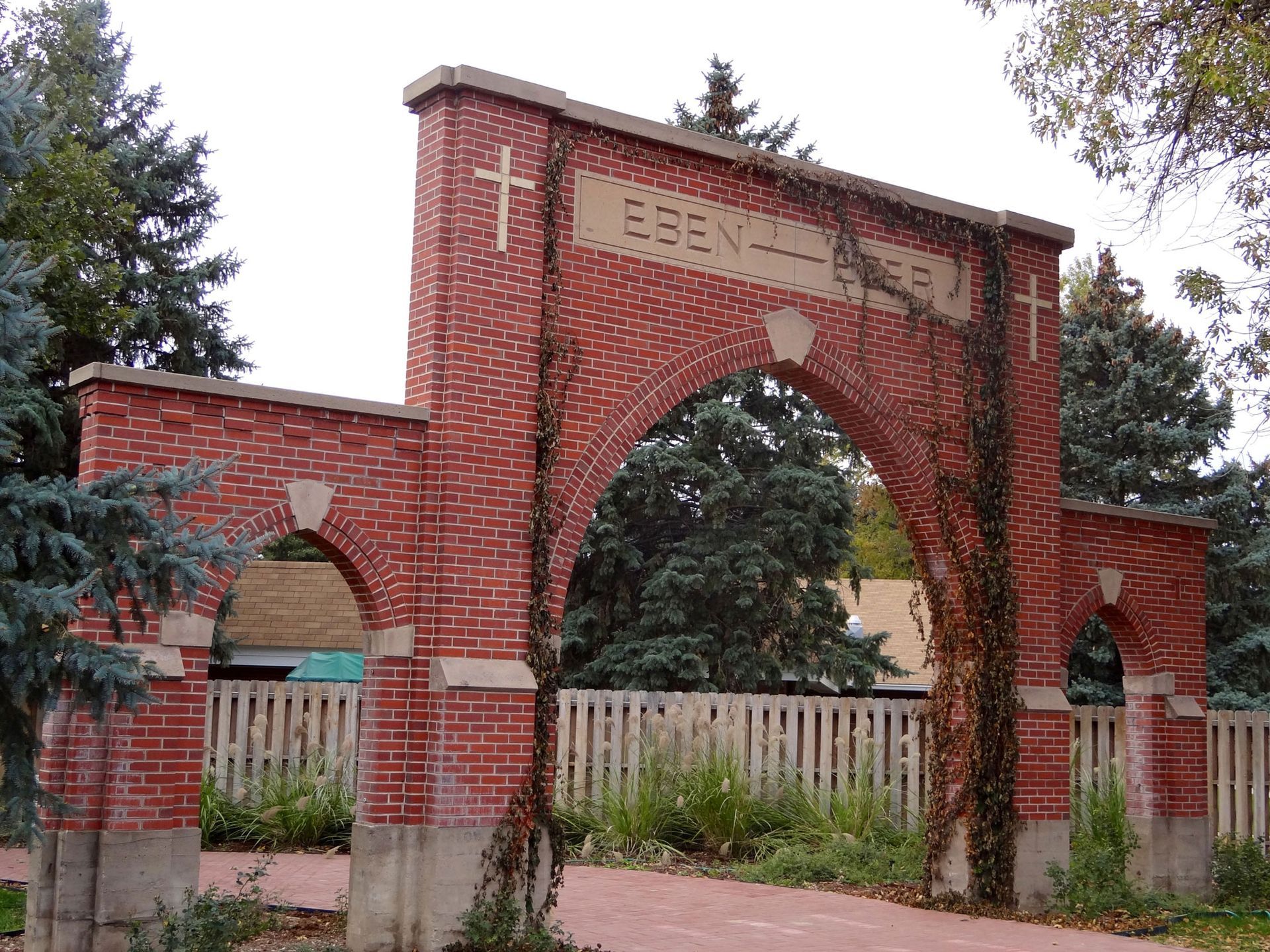 A red brick archway with a central pointed arch and two smaller flanking arches, engraved with the word 