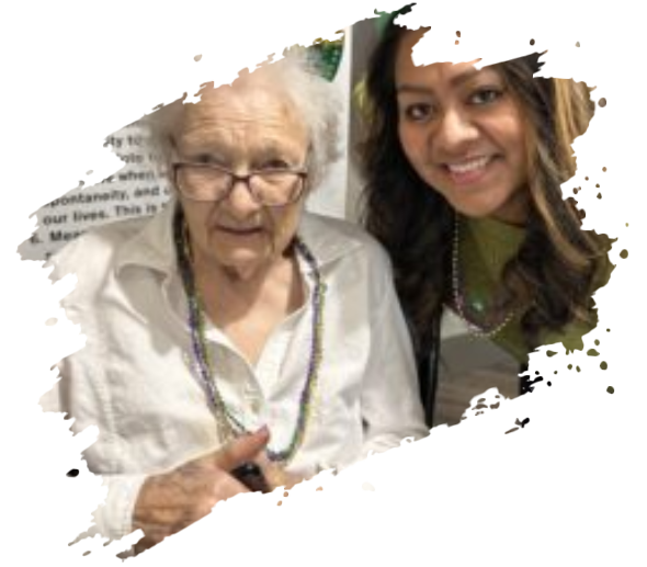 An older woman and younger woman smile, wearing Mardi Gras beads.