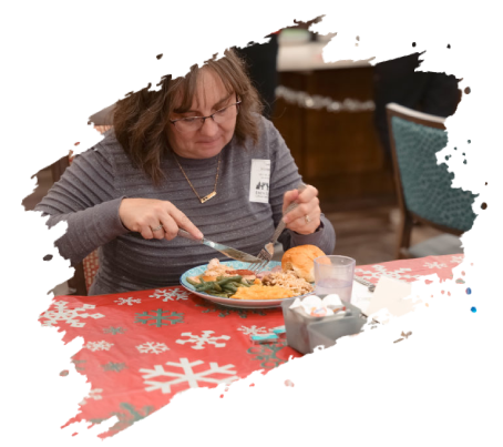 Woman with glasses eating at a Christmas-themed table, with food, napkin, and a drink.